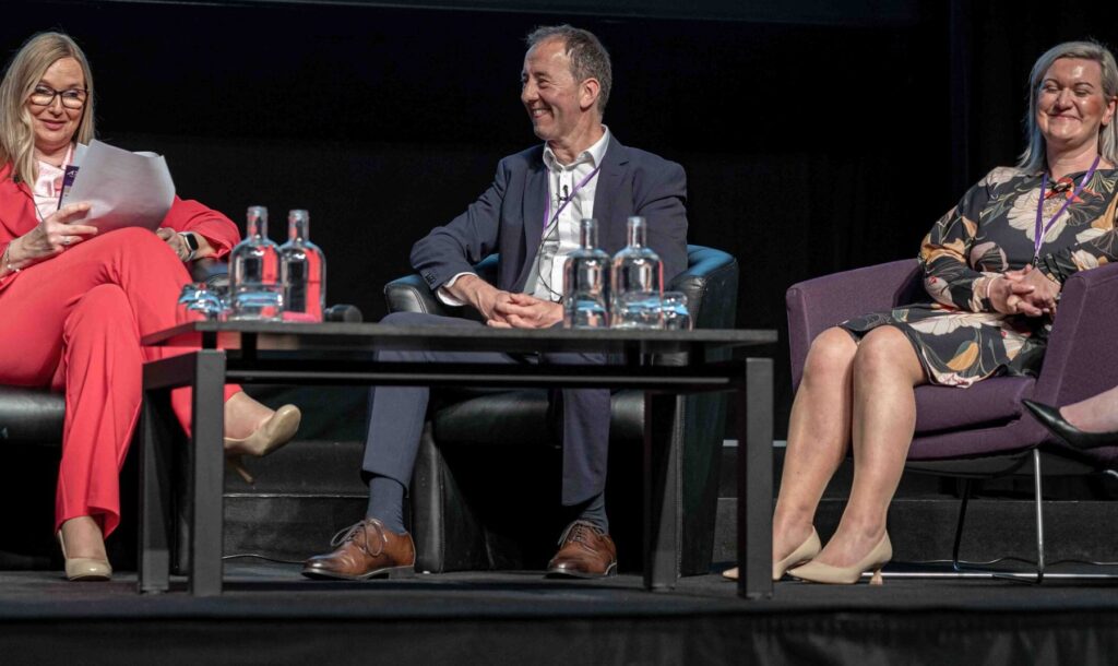 Trzy osoby podczas panelu dyskusyjnego na scenie